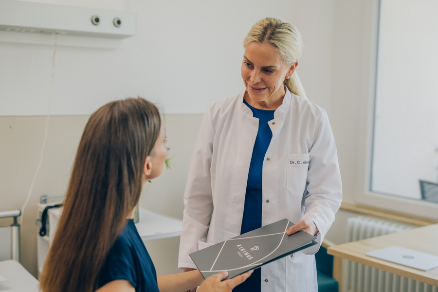 Eine Ärztin in einem weißen Kittel überreicht einer Patientin eine Broschüre.